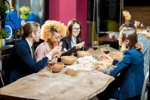 Group of people enjoying food and wine around a large live edge dining table in Ottawa.