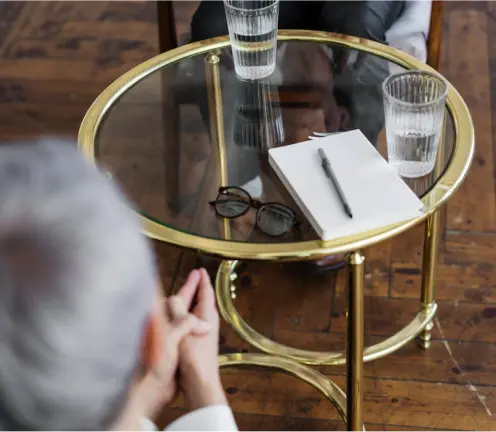Glass round table with notebook, pen, glasses, and two glasses of water symbolizing stylish and functional alternatives like live edge tables in Ottawa.