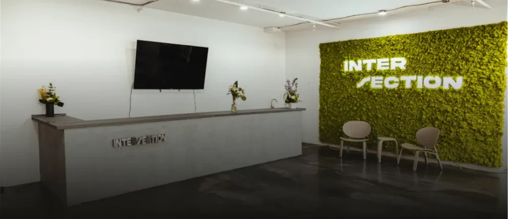 Reception area with green moss wall, modern chairs, and custom live edge tables in Ottawa.