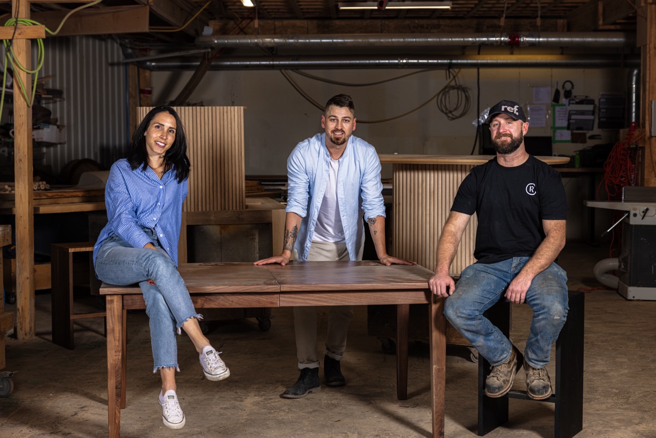 Three Ottawa furniture makers in a workshop showcasing their craftsmanship behind live edge tables.
